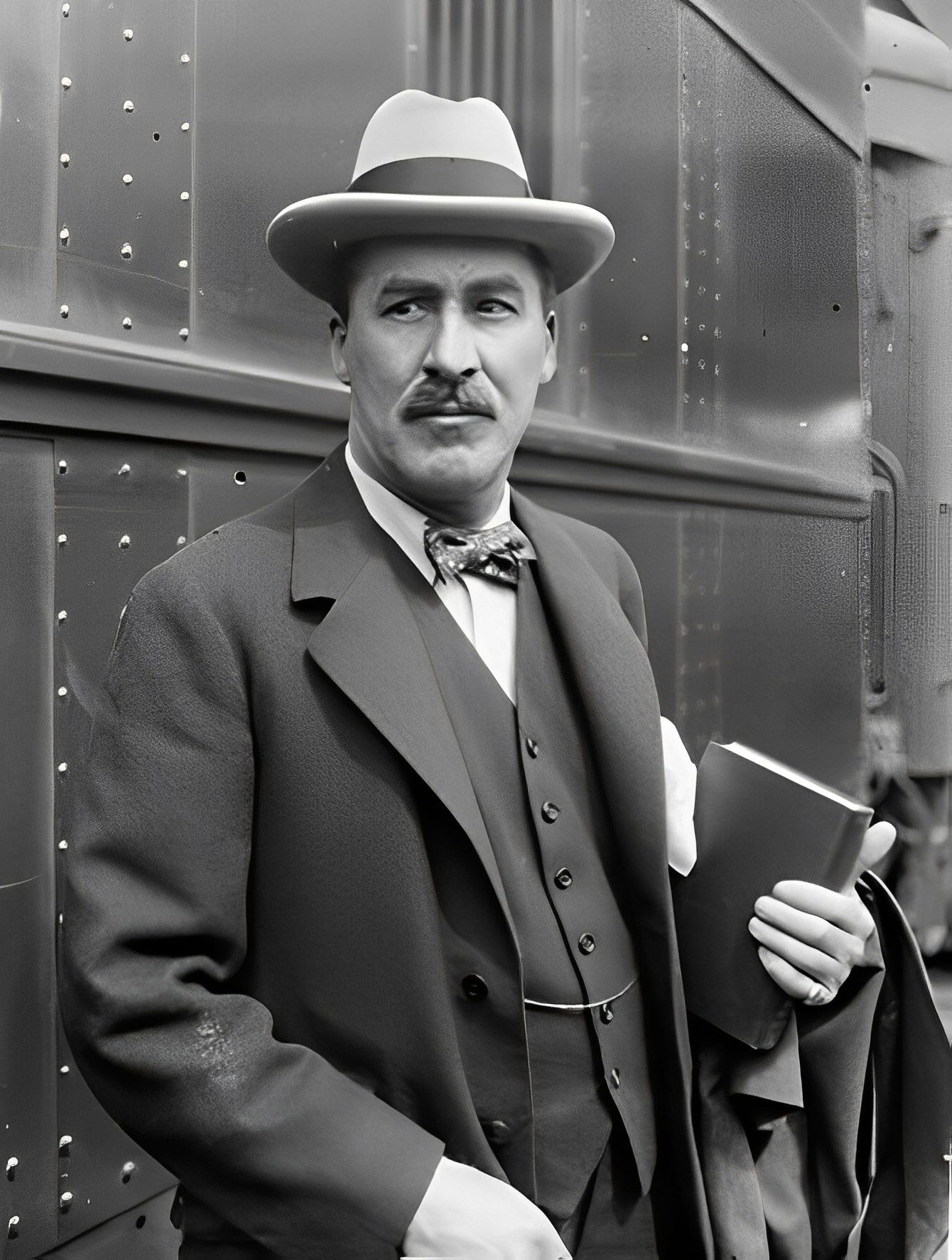 Informal portrait of howard carter the archaeologist standing with a book in his hand next to a train at a station in chicago illinois